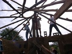 some people are standing on the roof of a building that is being built with wooden beams