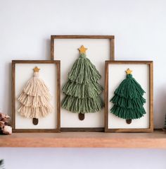 three framed christmas trees on a shelf with pine cones in the bottom, and one decorated as a fir tree