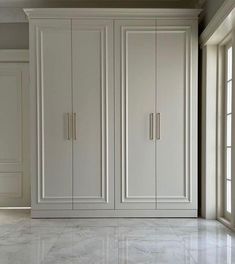 an empty room with white cabinets and marble floors