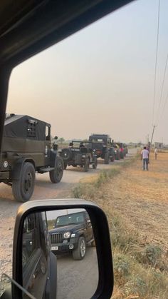 several jeeps are parked on the side of the road as people walk by in the distance