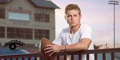 a man holding a football sitting on top of a wooden fence next to a building