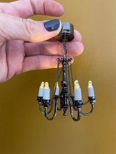 a person is holding a miniature chandelier with five lights attached to the chain