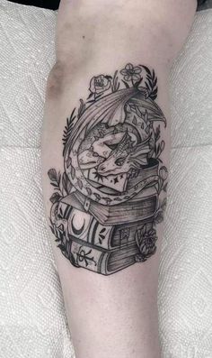 a black and white tattoo on the leg of a person with books in their hands