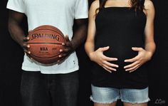 two people standing next to each other with a basketball on their belly and one holding the ball