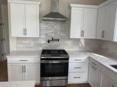 a stove top oven sitting inside of a kitchen next to white cupboards and drawers