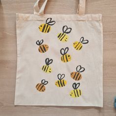 a white bag with yellow and black bees on it next to some blue yarn balls