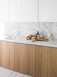 a kitchen with white marble counter tops and wooden cabinetry, along with soap dispensers