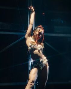 a woman is performing on stage with her hands in the air and one leg up