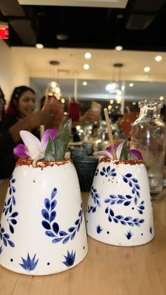 two blue and white vases with flowers on them sitting on a table in a store