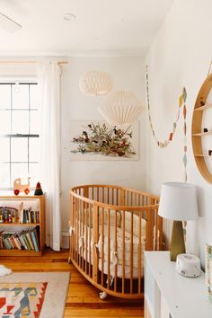 a baby's room with a crib, bookshelf, and window