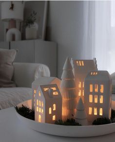 a white plate topped with lit up houses on top of a table next to a window