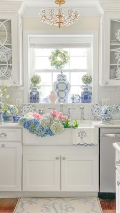 a white kitchen with blue and white decor on the window sill above the sink