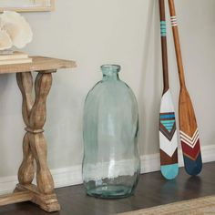 two paddles and a glass bottle are on the floor next to a small table