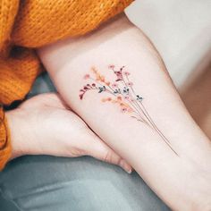 a small flower tattoo on the left inner forearm and wrist is shown in front of a woman's arm