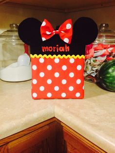 a minnie mouse bag with a name on it sitting on a kitchen counter next to some watermelon