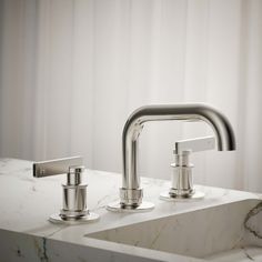 two faucets sitting on top of a marble countertop next to a sink