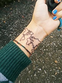 a woman's wrist with a world map tattoo on it