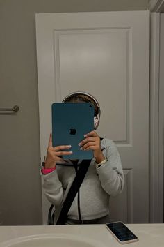 a woman taking a selfie in front of a mirror with an ipad and headphones