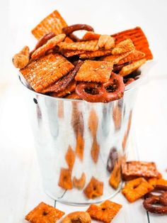 a metal bucket filled with cheetos sitting on top of a white table next to crackers