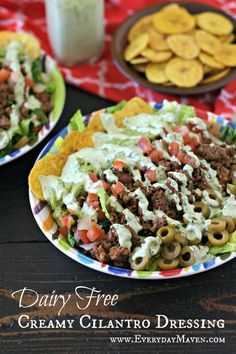 two plates filled with taco salad next to chips and ranch dressing on a table