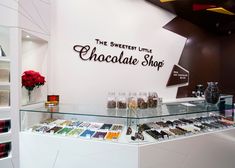 the sweetest little chocolate shop is located in an upscale shopping area with glass shelves