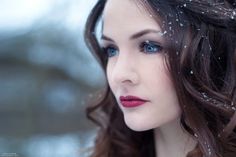 a woman with long brown hair and blue eyes is wearing snow flakes on her head