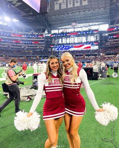 two cheerleaders posing for the camera at a football game