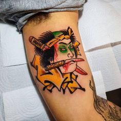 a person with a tattoo on their arm holding a knife and wearing a green mask