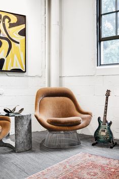 an egg chair and footstool sit in front of a painting on the wall