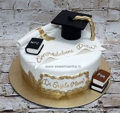 a graduation cake is decorated with white frosting and gold trim, topped with a black tassel