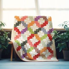 a quilted blanket sitting on top of a wooden chair next to potted plants