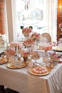 a table topped with lots of desserts next to a tall vase filled with flowers