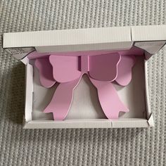 an open box with two pink bows on the front and one bow on the back