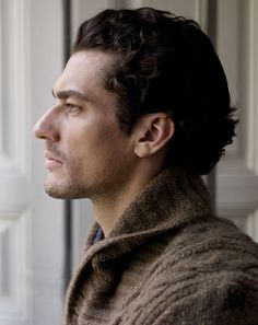 a man in a brown sweater looking off into the distance