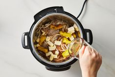 someone pouring some liquid into an instant pot filled with food