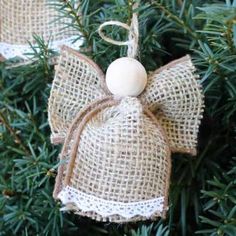 burlap angel ornament hanging from a christmas tree with white balls on it