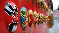 a row of colorful masks on a red wall