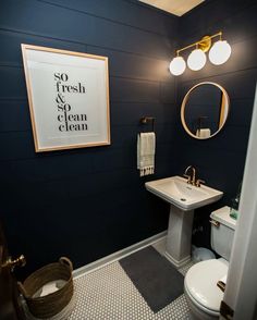 an instagram page showing a bathroom with black walls and white fixtures, including a gold framed mirror above the sink