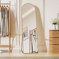 a mirror sitting on top of a wooden floor next to a dresser and clothes rack