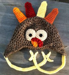 a crocheted turkey hat on top of a wooden table next to a pair of scissors