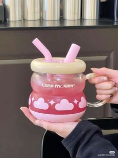 a person holding a pink cup with straws in it's mouth and the lid