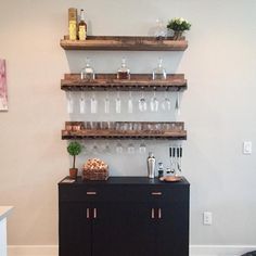 a bar with wine glasses and bottles on the top shelf next to a black cabinet