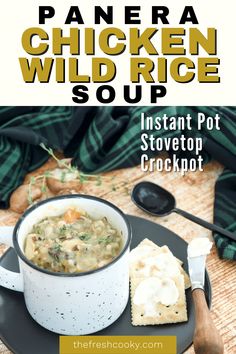 a bowl of chicken wild rice soup on a plate with crackers and spoons