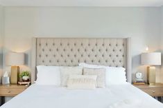 a bed with white linens and pillows in a small room next to two nightstands