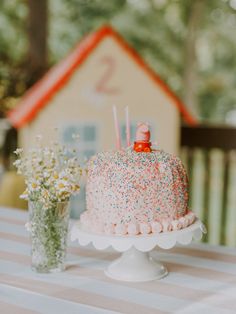 a birthday cake sitting on top of a table next to a vase filled with flowers