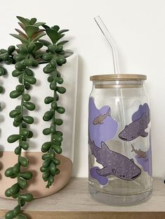 there is a glass jar with animals on it next to a plant and other items