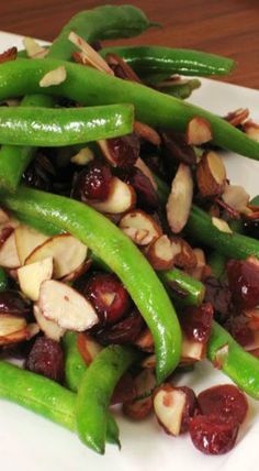 green beans, almonds and dried cherries on a white plate with wood table