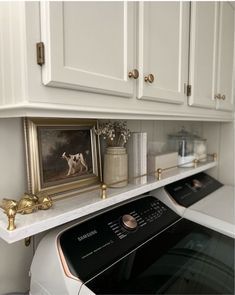 a white washer and dryer sitting in a kitchen next to cabinets with gold knobs