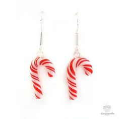 red and white candy cane earrings with silver earwires hanging from hooks on a white background