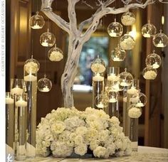 a centerpiece with flowers and candles on a table in front of a mirror wall